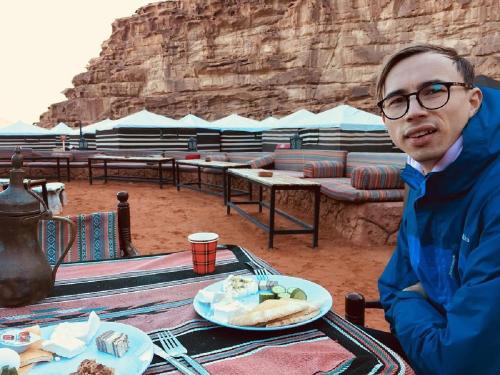 a man sitting at a table with a plate of food at Star World Camp in Wadi Rum