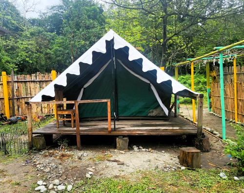 a tent with a chair on a wooden platform at Beyond Brahmaputra Campsite in Brahmakund