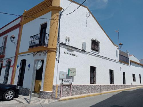 a white and yellow building with a car parked in front at An Ca La Abuela Pilar in El Real de la Jara