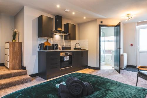 a kitchen with black cabinets and a stove at Luxury Central Derby Apartment in Derby
