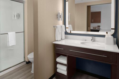 a bathroom with a sink and a toilet and a mirror at Homewood Suites By Hilton Charlotte Uptown First Ward in Charlotte