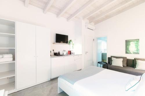 a white bedroom with a bed and a couch at Le Betulle Studios by Quokka 360 - studio apartments by the Origlio lake in Origlio