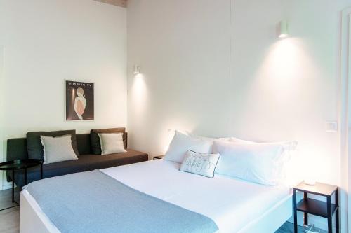 a bedroom with a large white bed and a couch at Le Betulle Studios by Quokka 360 - studio apartments by the Origlio lake in Origlio