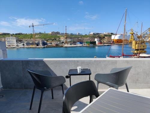 eine Terrasse mit Stühlen und einem Tisch mit Hafenblick in der Unterkunft Cabin 4 Savynomad Harbour Residences wow Views in Cospicua