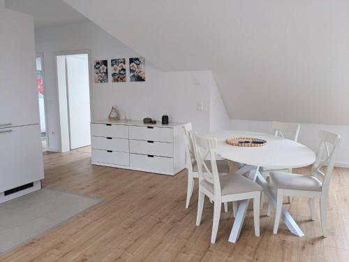 a white kitchen with a white table and chairs at Familienglück direkt am Radweg zum Steinhuder Meer in Wunstorf