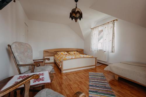 a bedroom with a bed and a chair and a window at Kaffai Panzio in Izvoru Mureşului