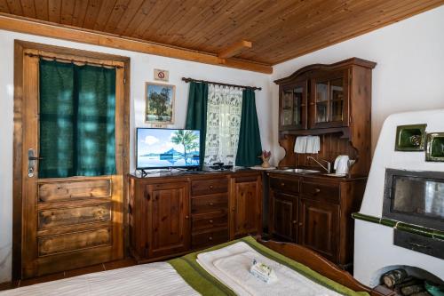 a kitchen with wooden cabinets and a television in a room at Pristava Lepena Village in Lepena