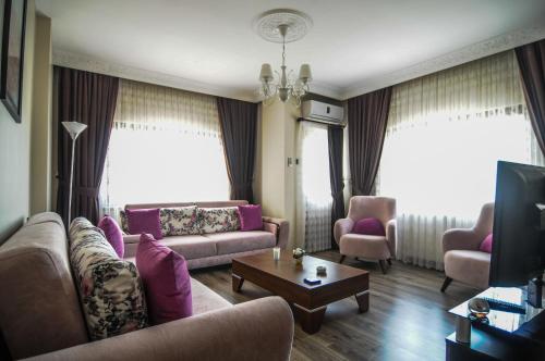 sala de estar con sofá, sillas y TV en Doa Apartment, en Trabzon