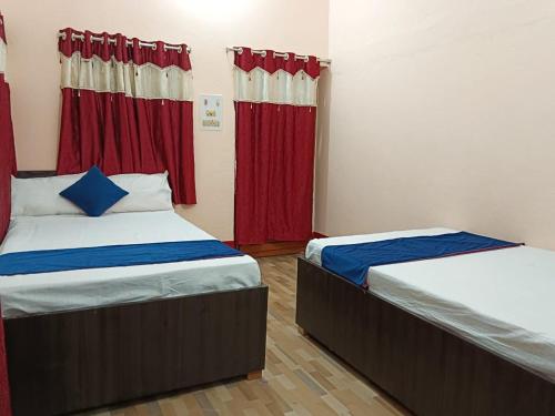 two beds in a room with red curtains at HOTEL SWASTIK "free pick up from station & airport" in Deoghar