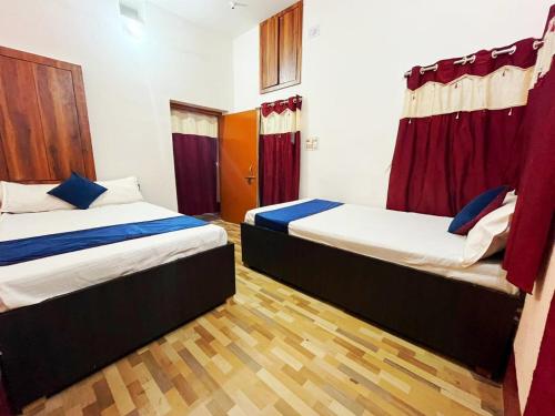 duas camas num quarto com cortinas vermelhas em HOTEL SWASTIK "free pick up from station & airport" em Deoghar