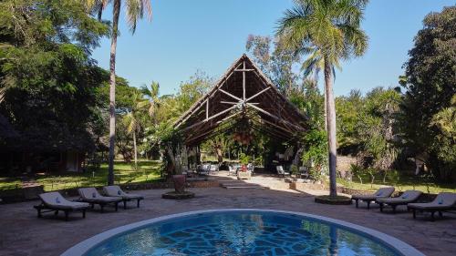 a swimming pool in front of a pavilion with palm trees at Saffron Garden Malindi in Malindi
