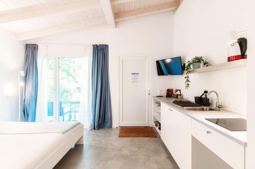a white kitchen with a sink and a counter top at Le Betulle Studios by Quokka 360 - studio apartments by the Origlio lake in Origlio