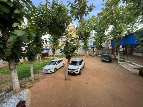 dois carros brancos estacionados num terreno sujo com árvores em HOTEL SWASTIK "free pick up from station & airport" em Deoghar