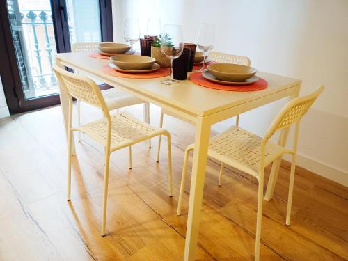 stół jadalny z krzesłami i stół z naczyniami w obiekcie Private rooms in Born w Barcelonie