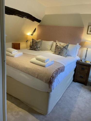a bedroom with a large bed with towels on it at Holly Cottage, 2, Northbrook Park, Farnham-up to 6 adults in Farnham