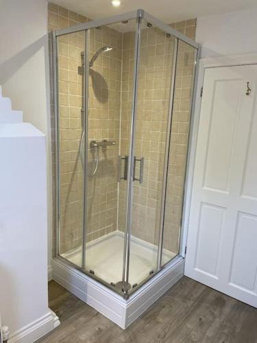 a shower with a glass door in a bathroom at Holly Cottage, 2, Northbrook Park, Farnham-up to 6 adults in Farnham