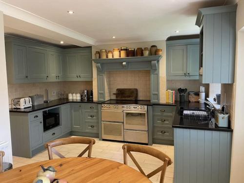 uma cozinha com armários azuis e uma mesa de madeira em Cottage 2, Northbrook Park, Farnham-up to 6 adults em Farnham