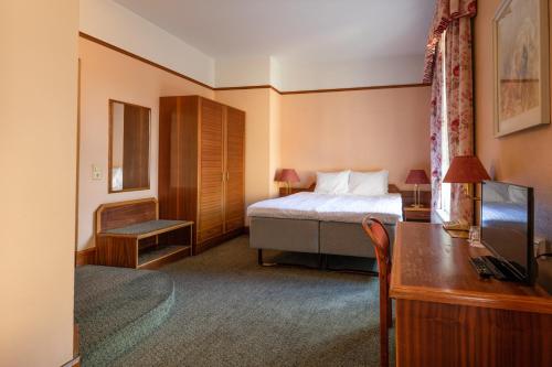 a hotel room with a bed and a desk and a television at Hotel Victoria in Pärnu