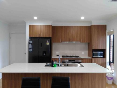 Happy House في Melton South: مطبخ مع مغسلة وثلاجة سوداء