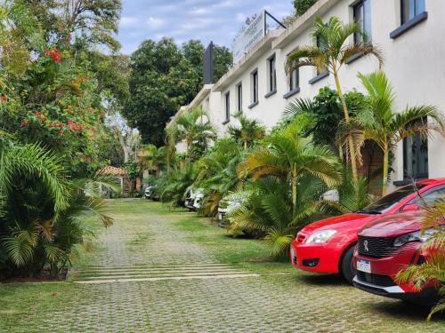um carro vermelho estacionado ao lado de um edifício com palmeiras em Hotel Oasis-Dream Holidays - La Petite France em San Bernardino