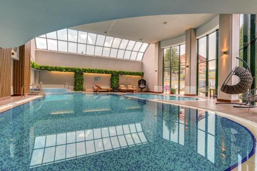 a large swimming pool in a building with a large window at Grand Hotel Murgavets in Pamporovo