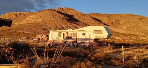 a white rv sitting on tracks in front of a mountain at Top Camp Sites at Desert Gardens Oasis at Lobo, Texas 
