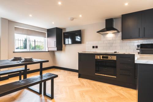 a kitchen with black cabinets and a table and a table and a stove at Dreamy Derby City Apartment Free Wi-Fi & Parking in Derby