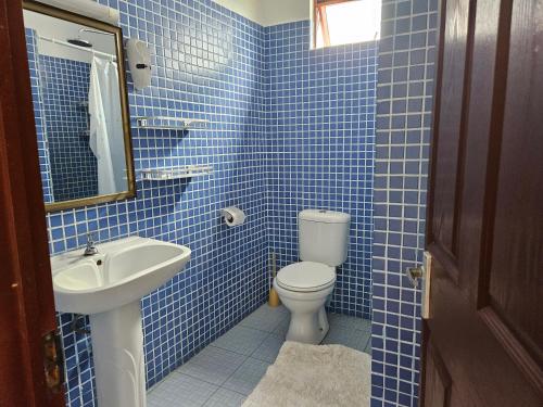 Baño de azulejos azules con aseo y lavamanos en Grand Bay Apartments en Grand Baie