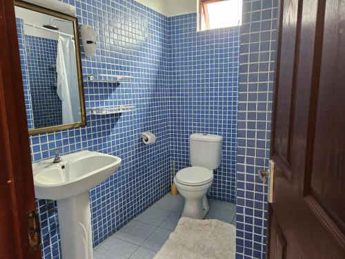 a blue tiled bathroom with a toilet and a sink at Grand Bay Apartments in Grand-Baie