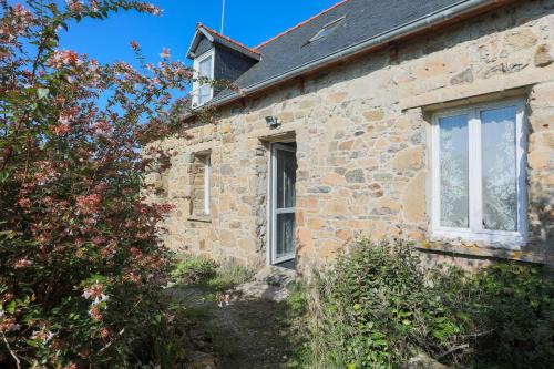 an old stone house with a window and plants at Maison pêcheur vue mer in Pleubian