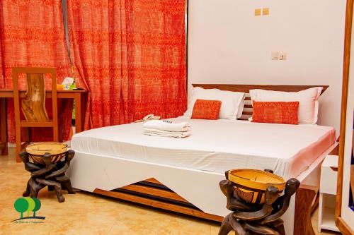 a bedroom with a large white bed with orange curtains at VILLA DE L'INTEGRATION in Ouagadougou