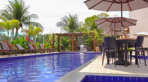 una piscina con sillas y sombrillas y una mesa con sombrilla en Altiplano Hotel, en João Pessoa