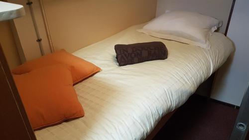 Una cama pequeña con una almohada naranja. en PÉNICHE authentique tout confort, en Aigues-Mortes