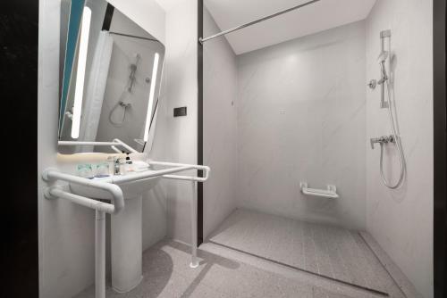 a white bathroom with a sink and a shower at Holiday Inn Express Shantou Chenghai in Shantou