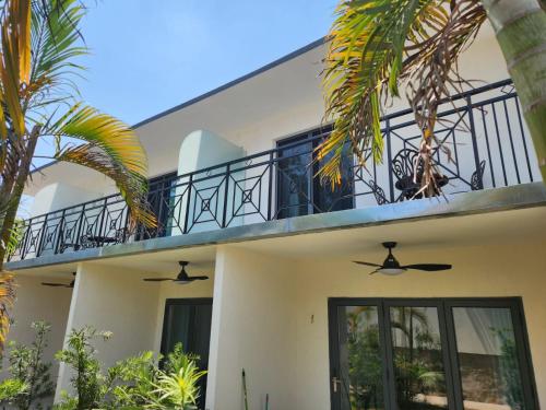a house with a balcony and palm trees at Hotel Oasis-Dream Holidays - La Petite France in San Bernardino