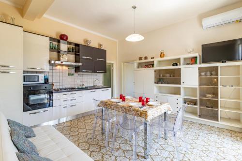 a kitchen with white cabinets and a table and chairs at Casa Lidia 900m From Sea - Happy Rentals in Lido di Camaiore