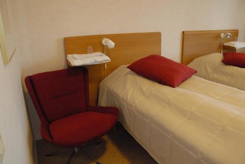 a hotel room with a red chair and a bed at Katrinebergs Folkhögskola B&B in Vessigebro