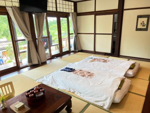 Cette chambre comprend un grand lit et une table. dans l'établissement เรียวกัง ยามะโฮชิ Ryokan Yamahoshi เชียงใหม่, à Chiang Dao