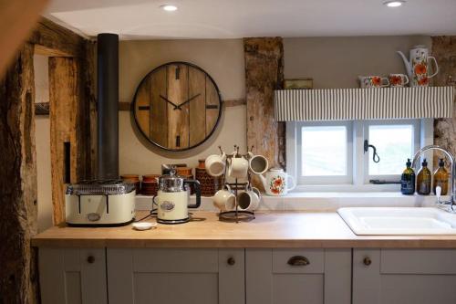 cocina con encimera con reloj en la pared en The Byre - Beautiful Contemporary Barn - Hot Tub, en Bridgnorth