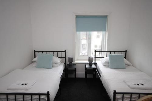 two twin beds in a room with a window at Central Beach Apartment & Free Parking in Blackpool