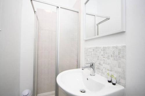 a white bathroom with a sink and a shower at Central Beach Apartment & Free Parking in Blackpool