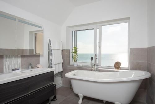 a bathroom with a large white tub and a window at Big Luxury House sleeps 12/14. Sea Views, Hot tub. in Hollington