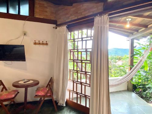 a room with a large window and a table and chairs at Pousada Morro do Forte in Paraty