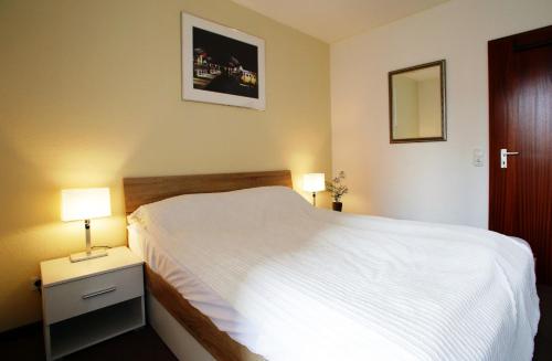 ein Schlafzimmer mit einem weißen Bett und zwei Lampen in der Unterkunft FeWo Zornemann Whg 1 Strandhotel in Kellenhusen