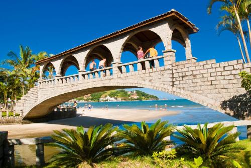 a bridge over a beach with people walking on it at Sofistic Hotel in Itapema