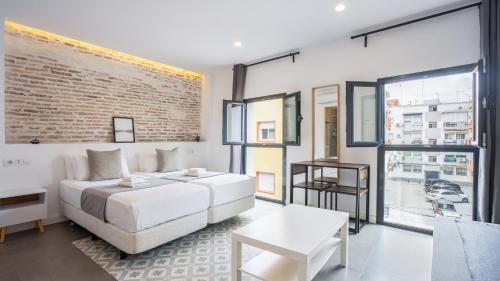 セビリアにあるDolium Apartmentsの白いベッドとレンガの壁が備わるベッドルーム1室が備わります。
