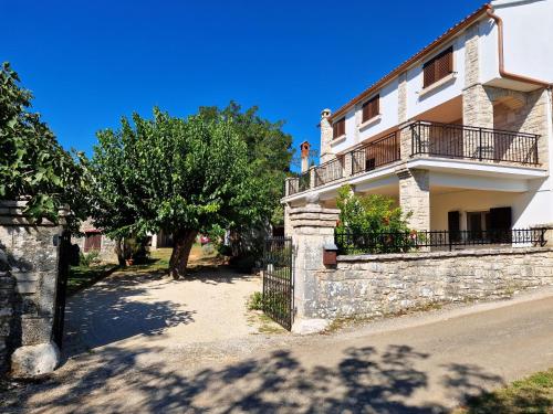 a white house with a stone wall and trees at Apartment Gina in Bale