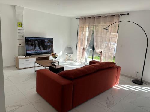 ein Wohnzimmer mit einem roten Sofa und einem TV in der Unterkunft LG1 in Saint-Dizier