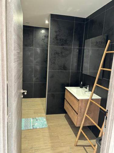 uma casa de banho com uma parede de azulejos pretos em LG1 em Saint-Dizier