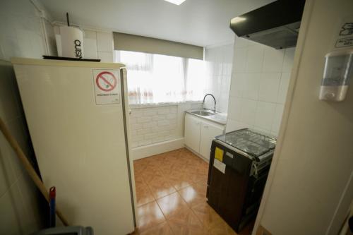 una pequeña cocina con fregadero y nevera. en Departamento Ovejero, en Punta Arenas